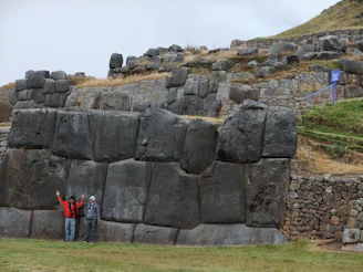 woman in red jacket standing beside gray rock formation during daytime