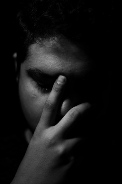 a black and white photo of a man holding his hand to his face