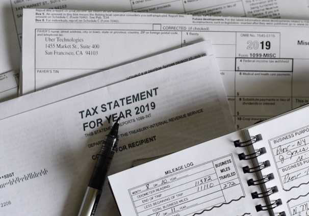 A collection of tax documents from 2019 and a mileage log with a pen