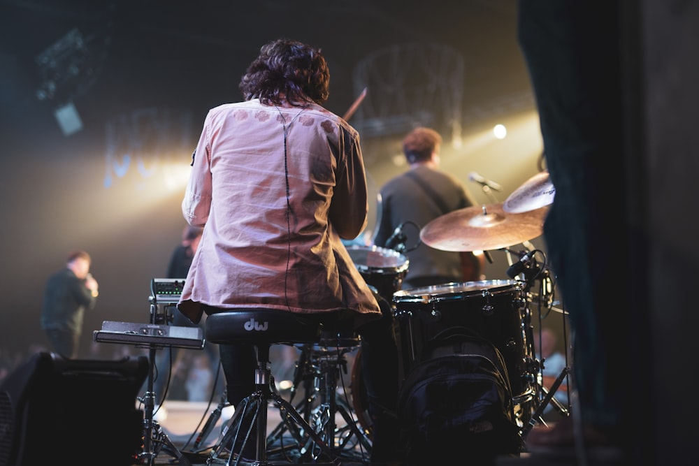 man in white dress shirt playing drum