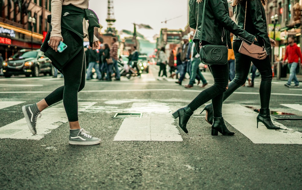 woman in black pants and black boots walking on street during daytime