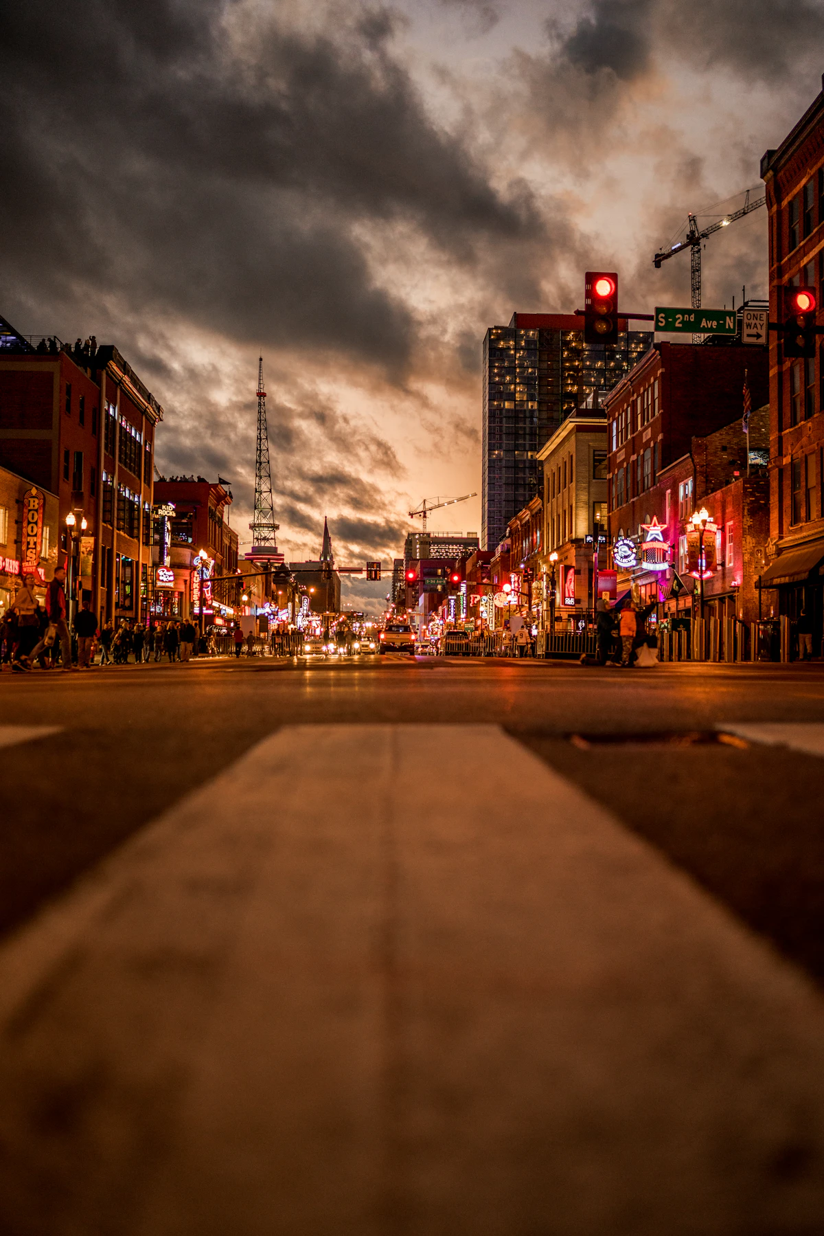 Lower Broadway in downtown Nashville at night, with neon-lit honky-tonks, traffic, and pedestrians