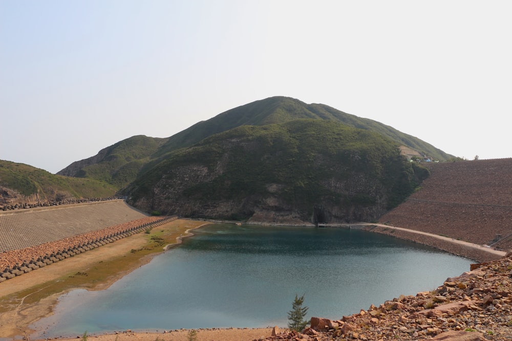 green mountain beside river under white sky during daytime