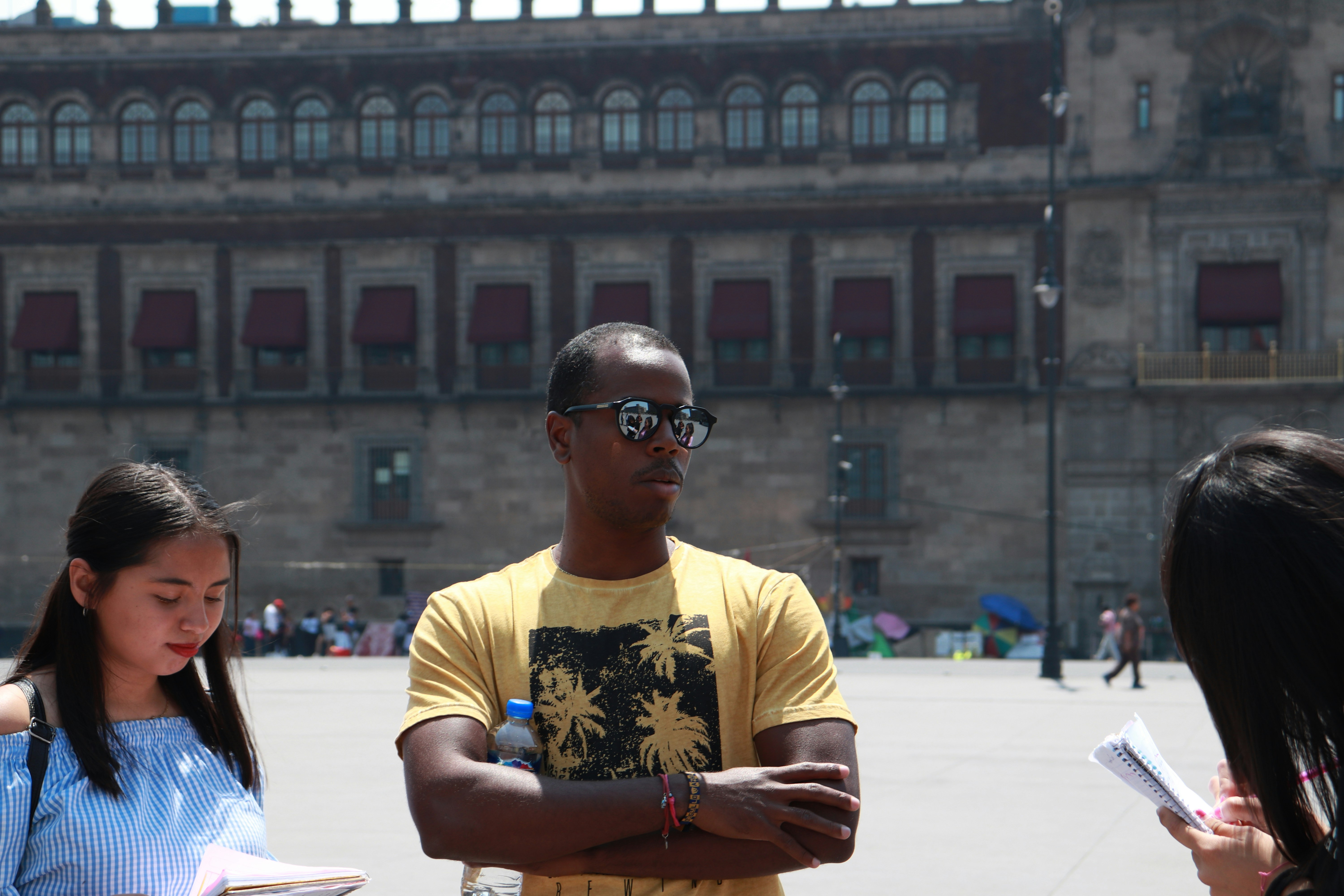 man in yellow crew neck t-shirt wearing black sunglasses sitting on chair
