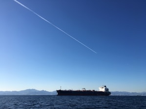A large cargo ship transporting oil across the ocean under a clear blue sky.