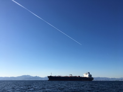 A large cargo ship transporting oil across the ocean under a clear blue sky.