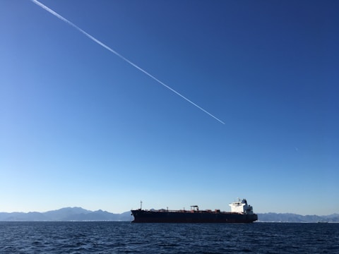 A large cargo ship sailing across the ocean under clear skies.