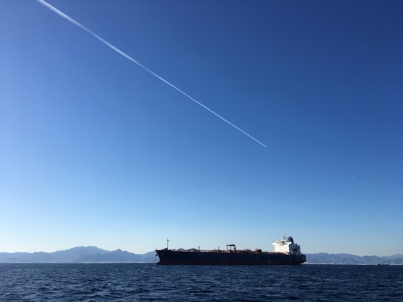 A large oil tanker sailing smoothly on the open sea under a clear sky.