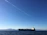 A sleek cargo ship loaded with containers sailing under a clear blue sky.