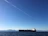 A sleek cargo ship loaded with containers sailing under a clear blue sky.