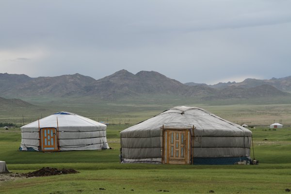 White and gray tent on green grass field near mountain under white clouds during daytime — Song-Köl, Kyrgyzstan