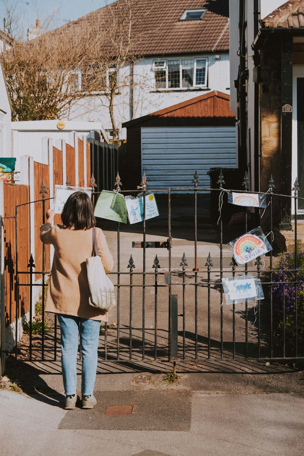 woman in beige long sleeve shirt and blue denim jeans holding green and white paper bags