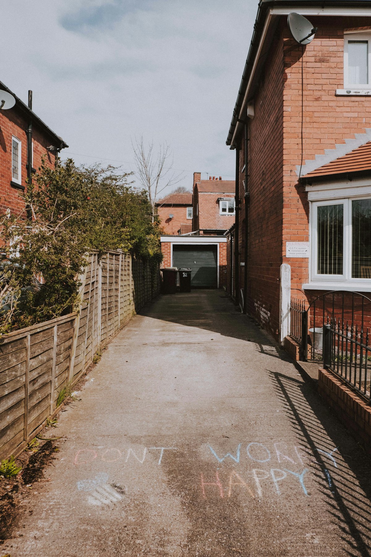 An old, worn concrete driveway between two brick houses