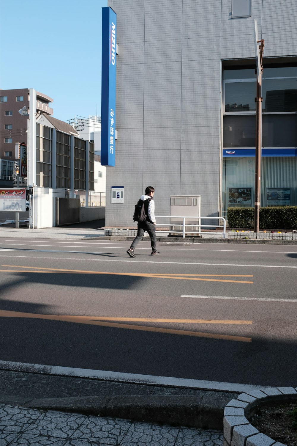 man in black jacket and black pants walking on sidewalk during daytime