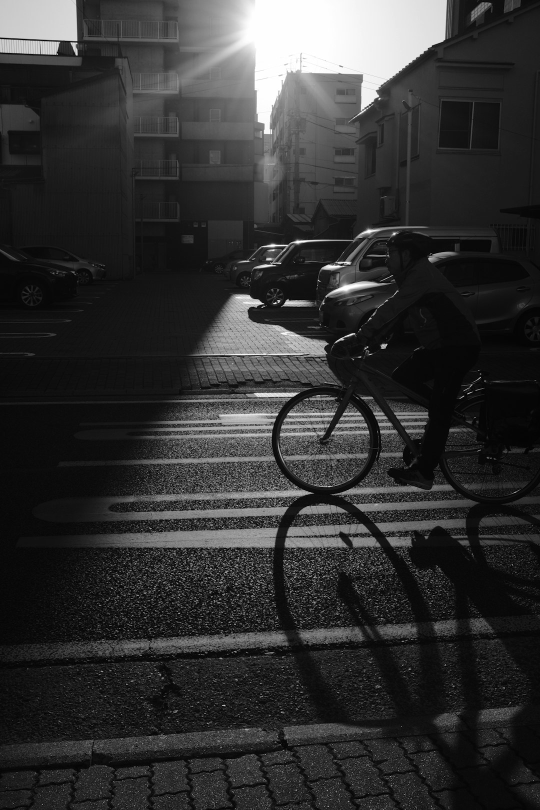 grayscale photo of man riding bicycle on road