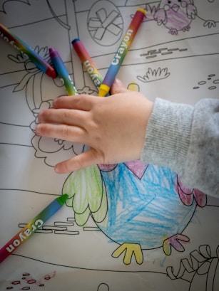person holding green and white coloring pencils