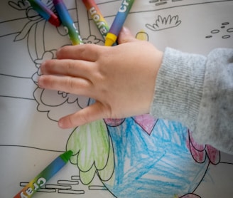 person holding green and white coloring pencils