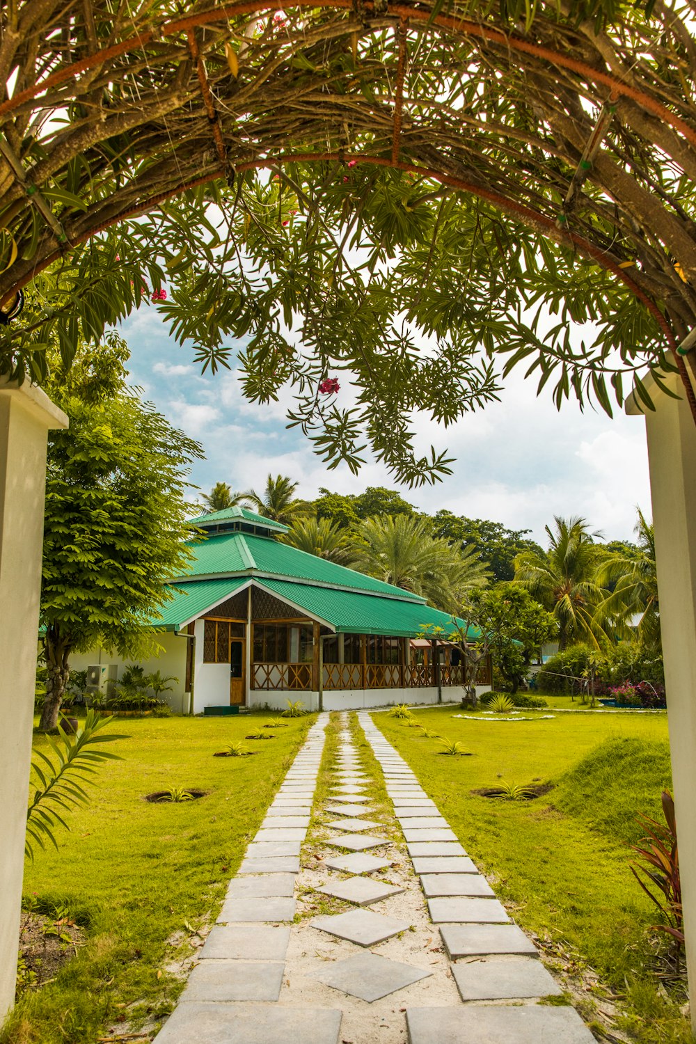 green and white wooden house near green trees under blue sky during daytime