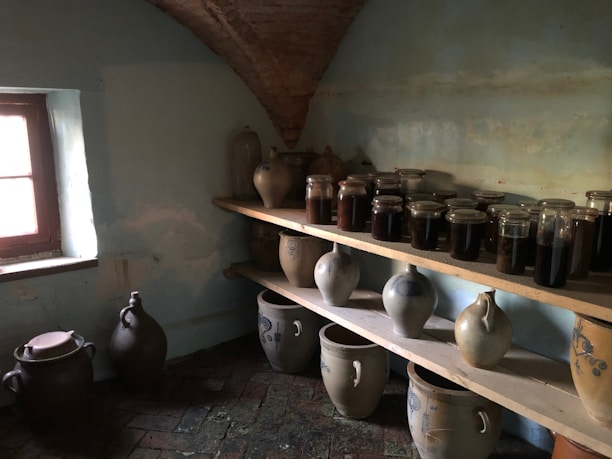 A cozy kitchen scene featuring a large fermenting vessel alongside smaller jars ready for storage.