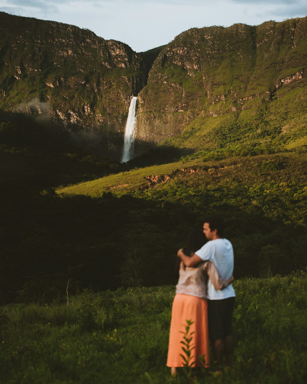 woman in white shirt and orange skirt standing on green grass field during daytime