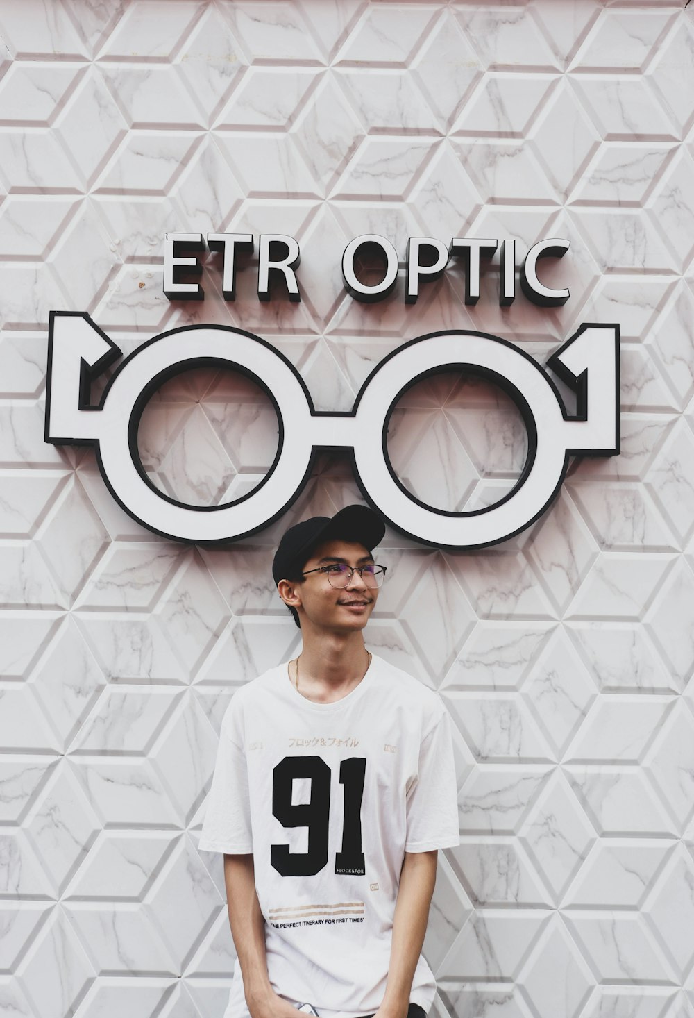 man in white crew neck t-shirt standing beside white wall