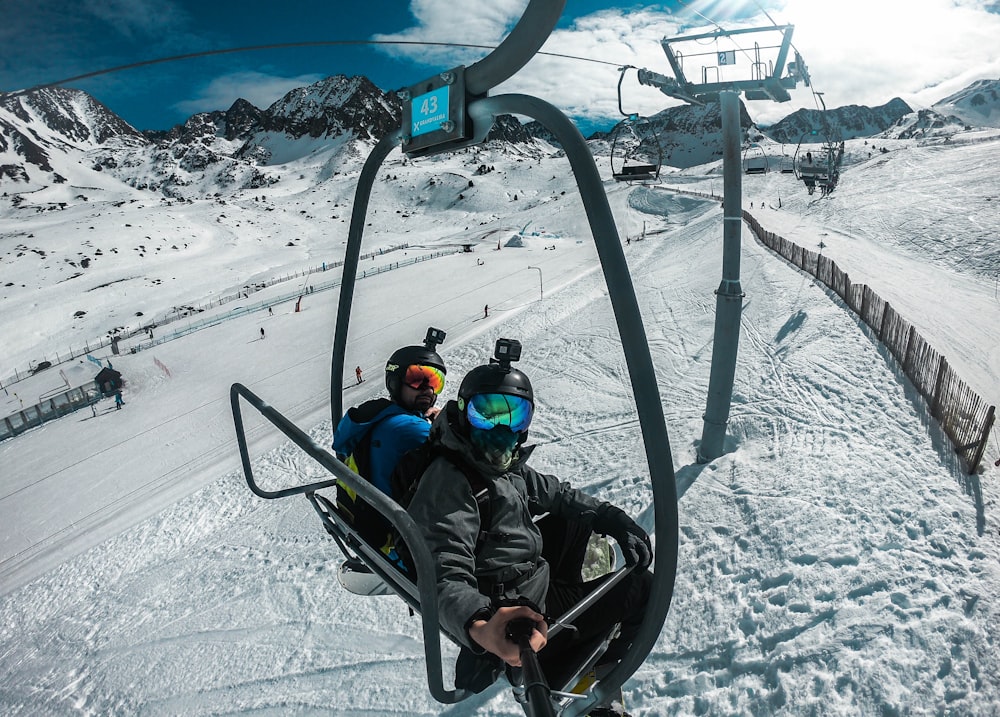 2 children riding on black ski lift during daytime
