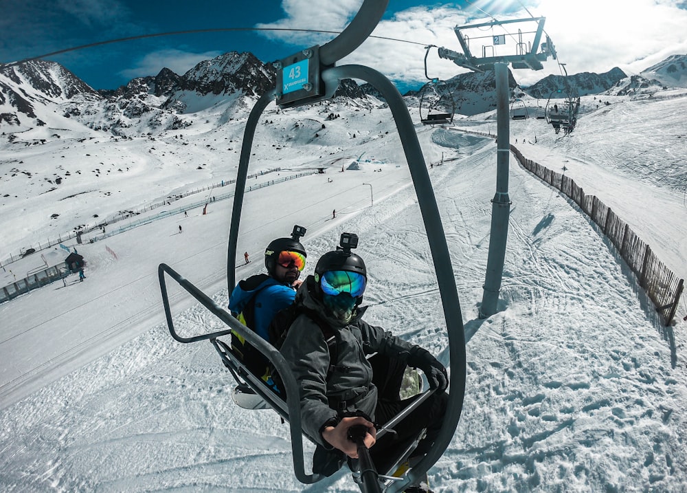 2 Kinder fahren tagsüber mit dem schwarzen Skilift