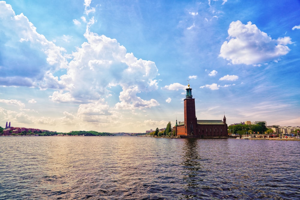 brown concrete building near body of water under white clouds and blue sky during daytime