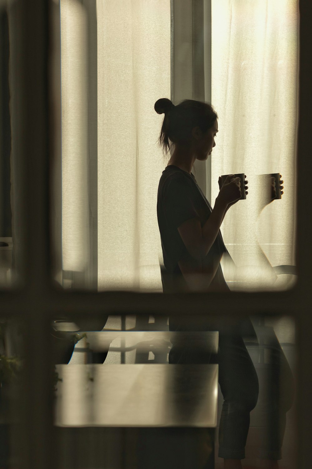 woman in black dress standing near window