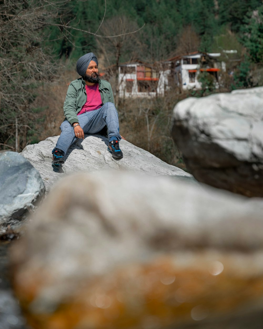 boy in blue jacket sitting on rock during daytime