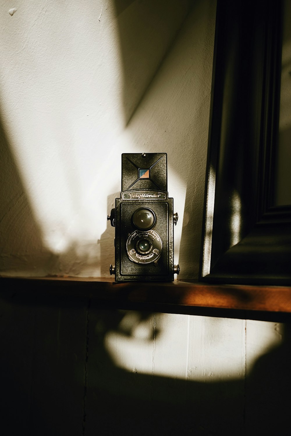 Fotocamera nera e argento su mensola in legno marrone