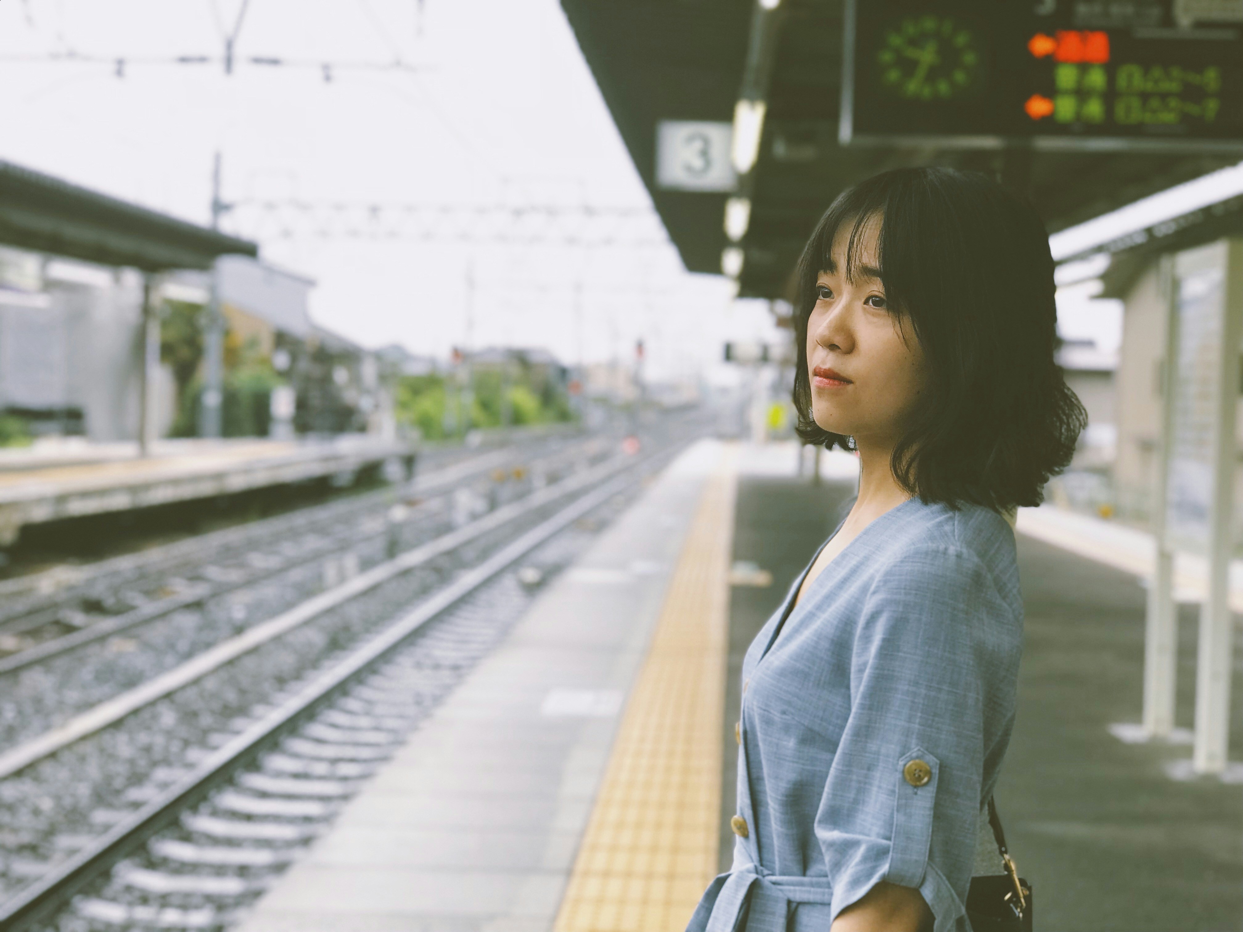 woman in blue denim jacket standing on train station during daytime