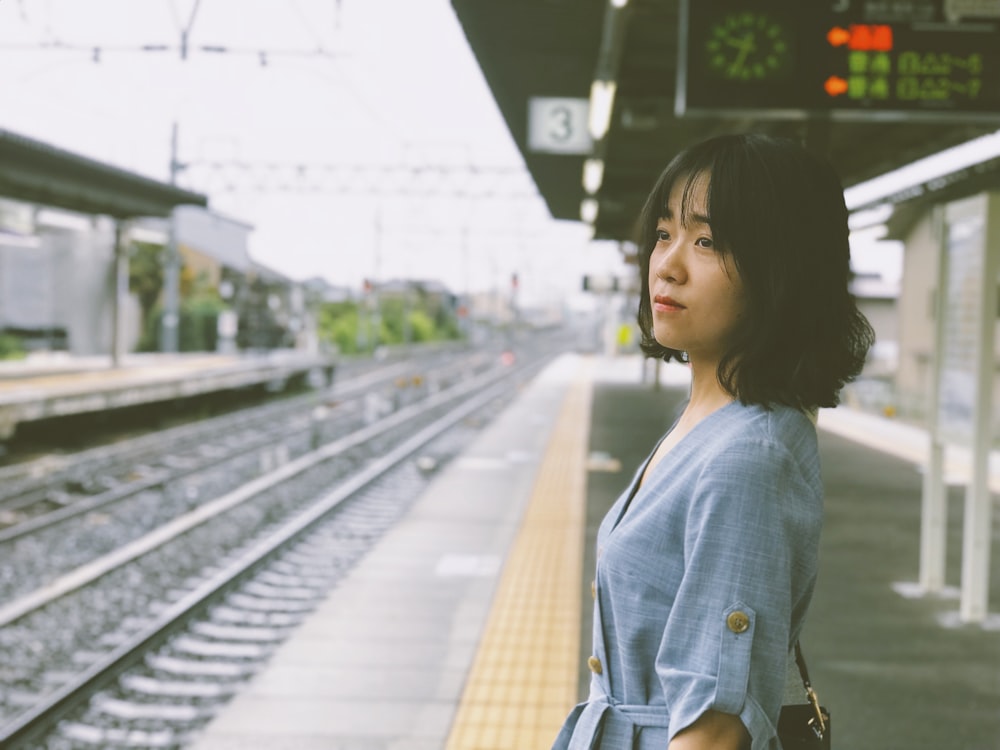 Femme en veste en jean bleu debout sur la gare pendant la journée