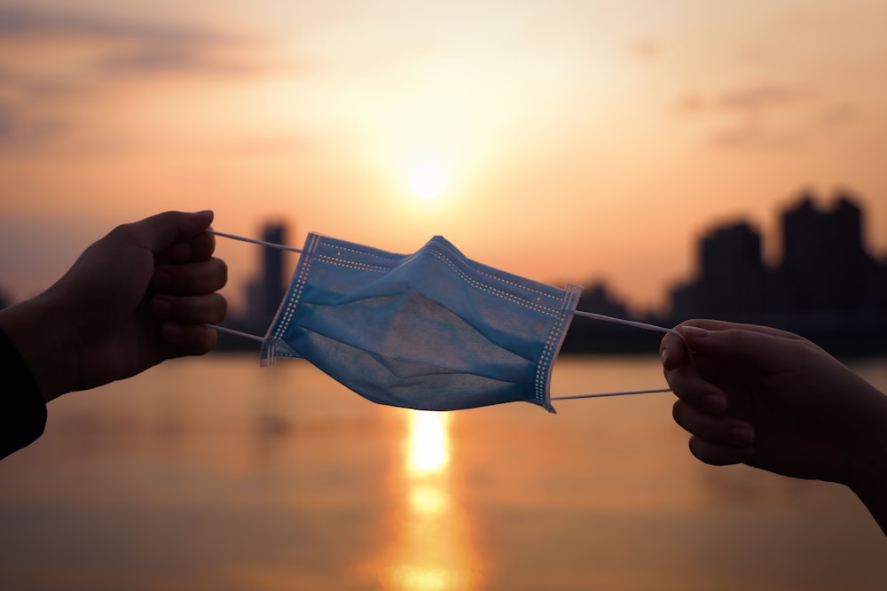 person holding blue and white underwear during sunset