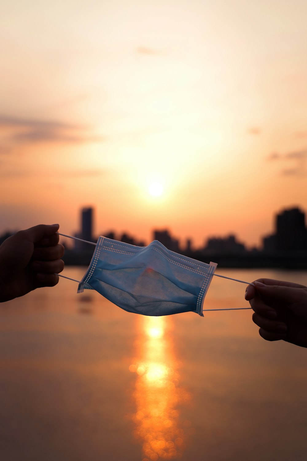 person holding white paper boat during sunset