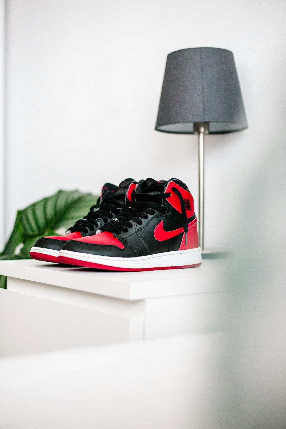 Schwarze und rote Nike Sneakers auf weißem Tisch