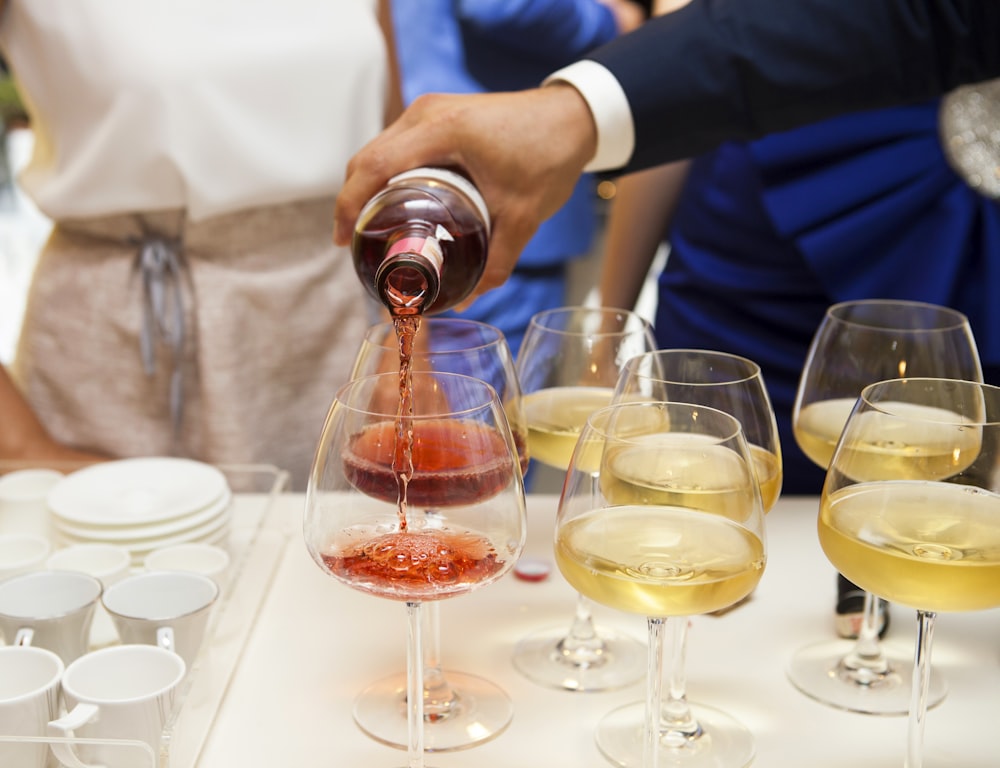 person pouring wine on wine glass