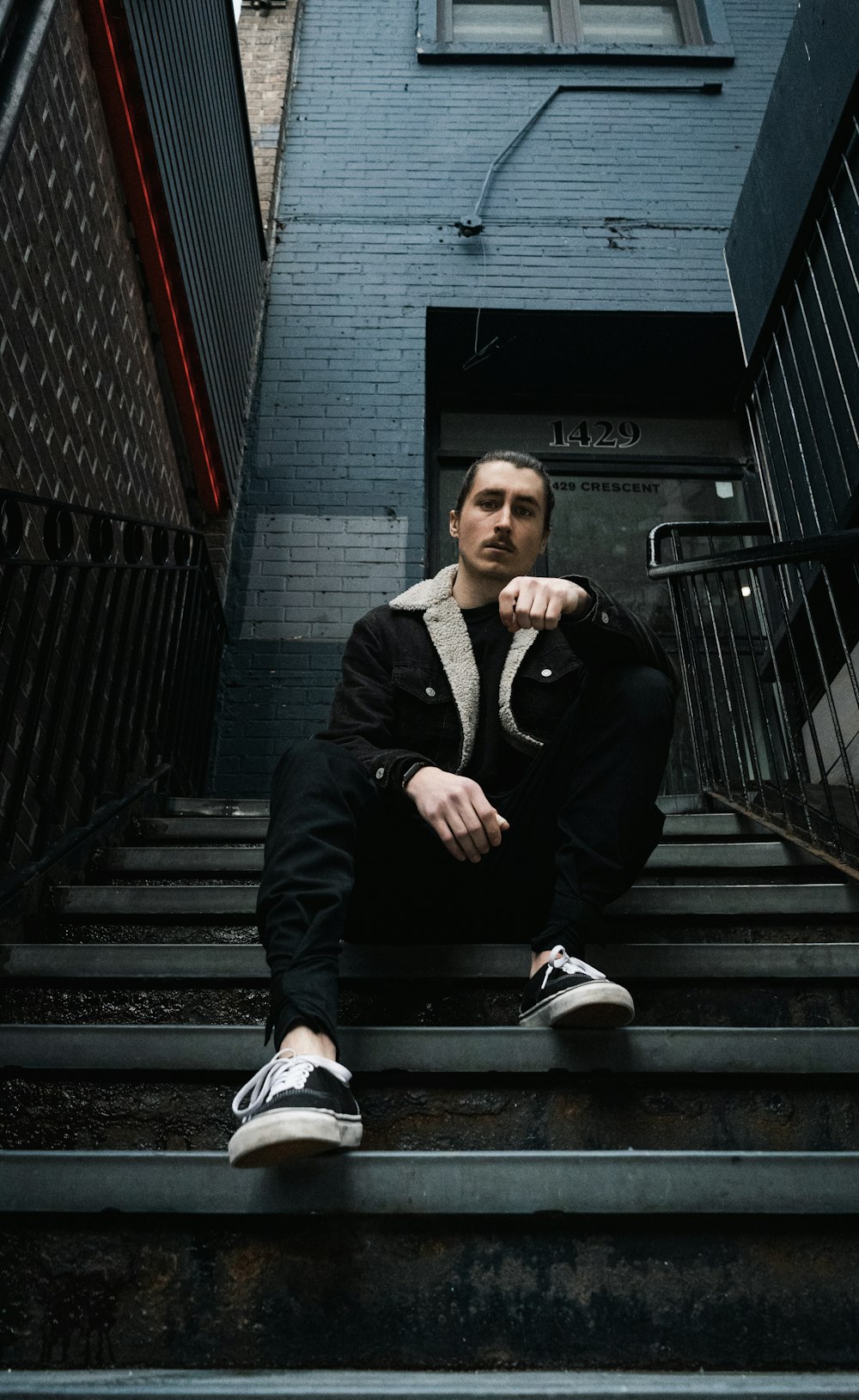 man in black blazer sitting on stairs