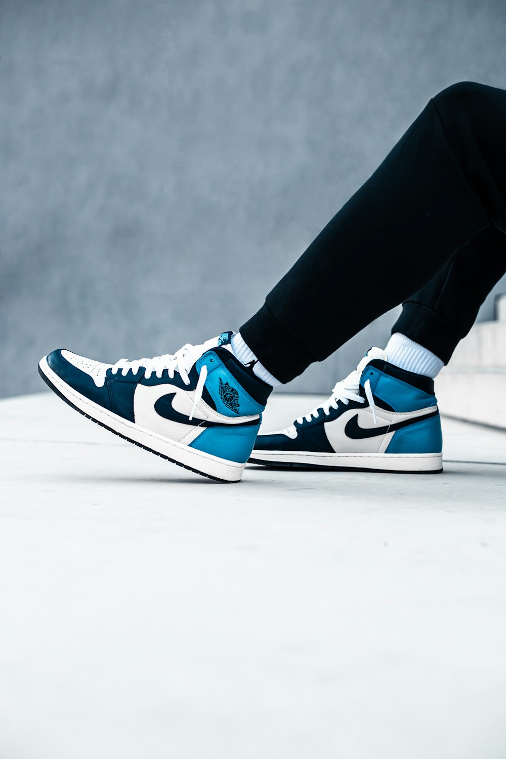 person wearing black pants and blue and white nike sneakers