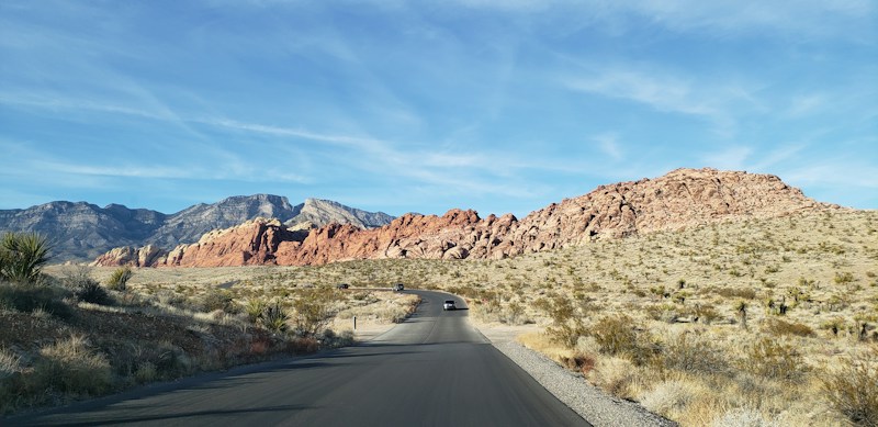 Paved desert road leading toward brown mountains near Las Vegas, like the Red Rock views west of Summerlin