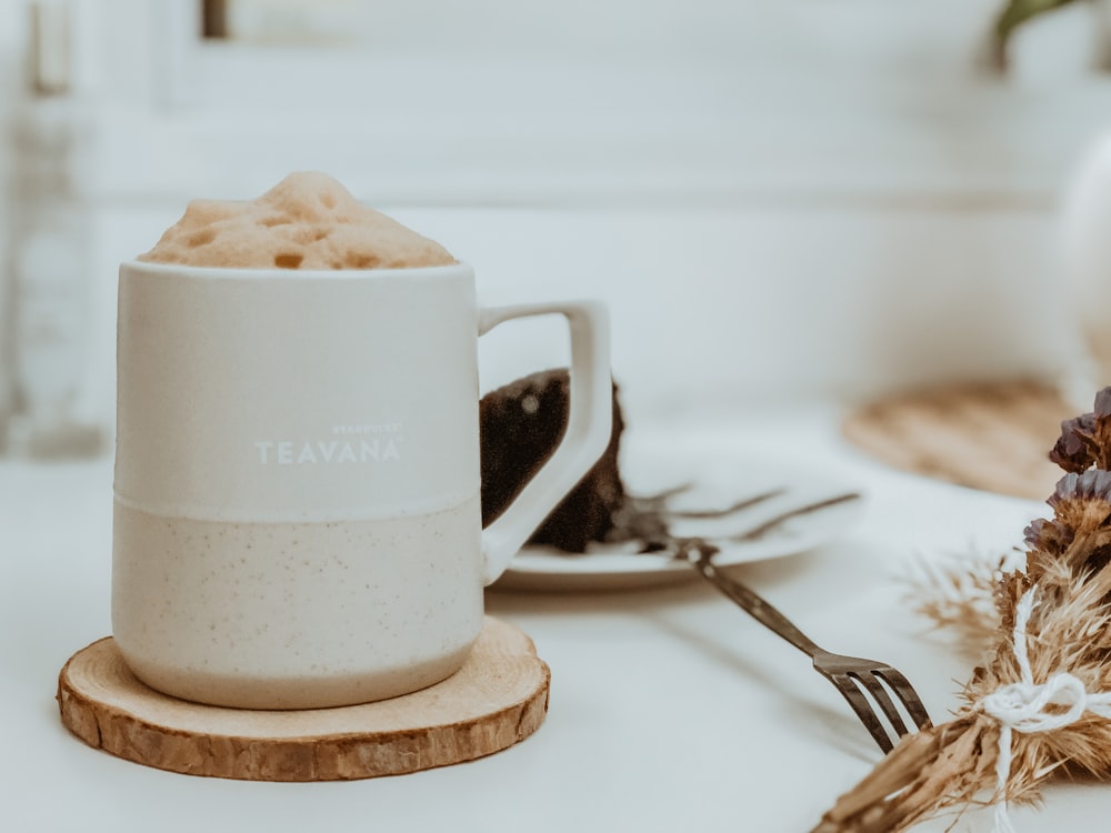 white ceramic mug beside stainless steel fork on white ceramic plate