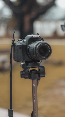 A professional DSLR camera with a zoom lens against a blurred cityscape background.