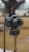 A professional DSLR camera mounted on a tripod, outdoors with a blurred background of trees and grass.