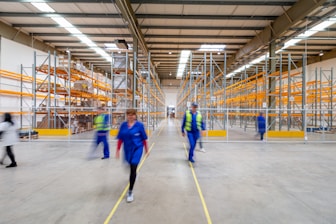 man in blue jacket and blue pants walking on yellow metal frame