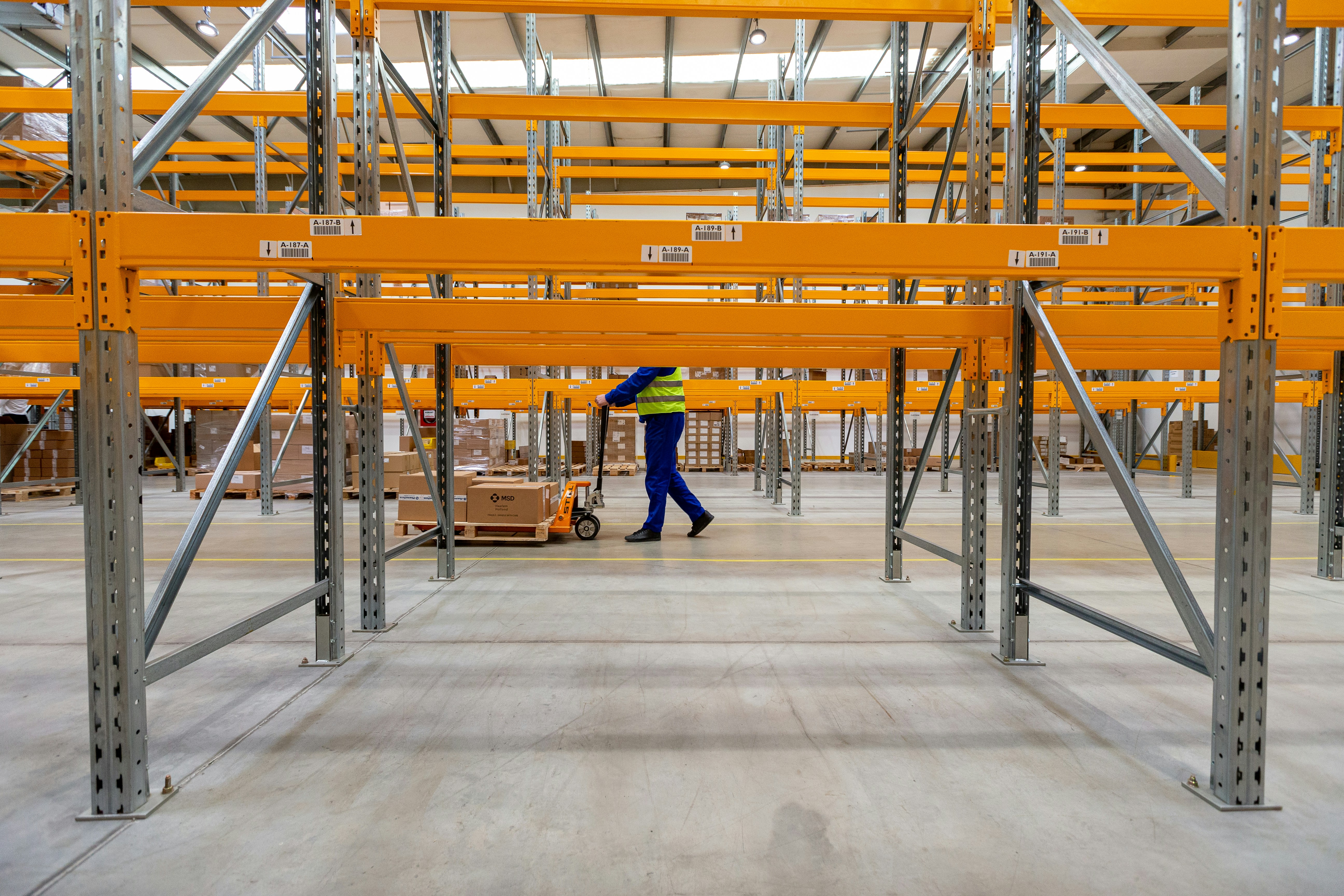 An aerial view of a group of warehouse workers in yellow hard hats standing in formation.