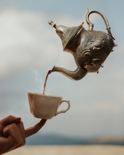 person holding white ceramic teapot