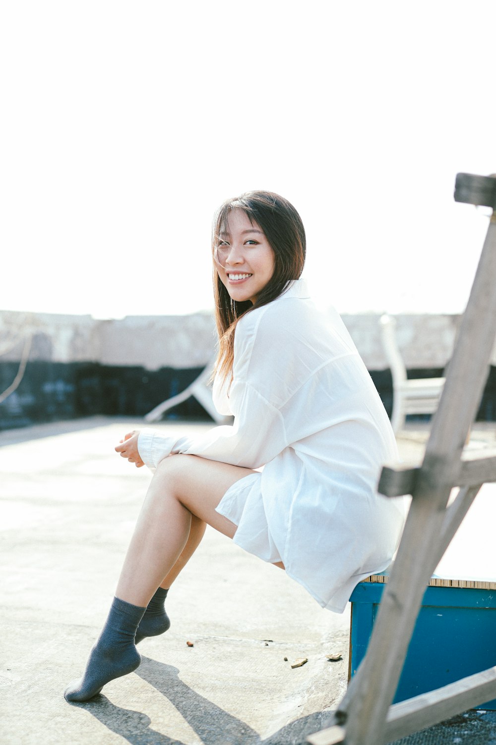 woman in white robe sitting on blue wooden bench during daytime