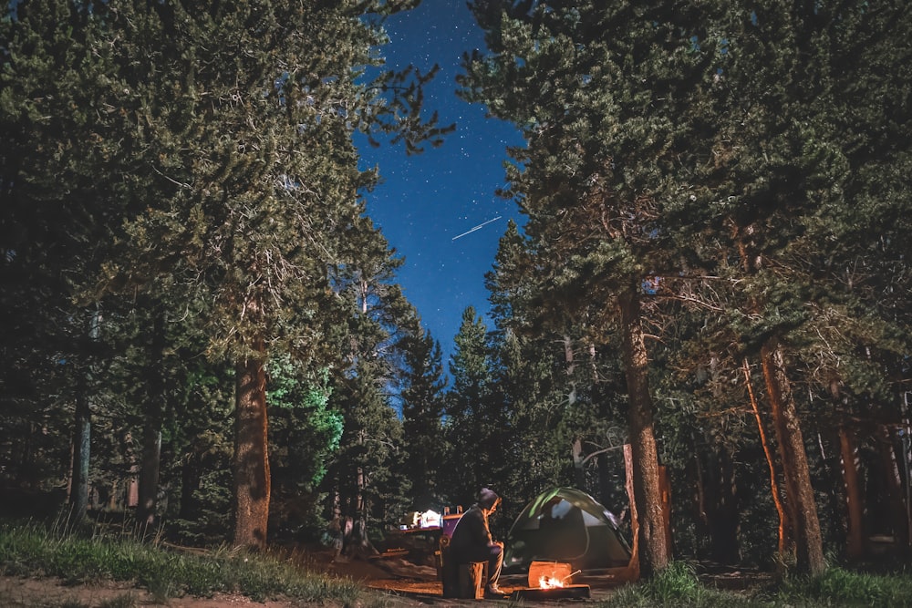 people sitting on camping chairs near bonfire under blue sky during night time