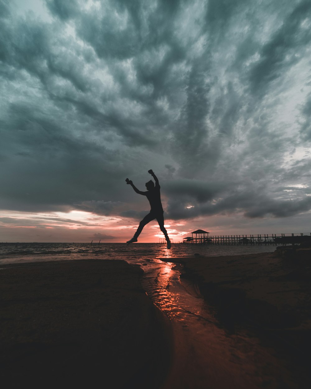 woman in black long sleeve shirt and black pants standing on brown sand during daytime