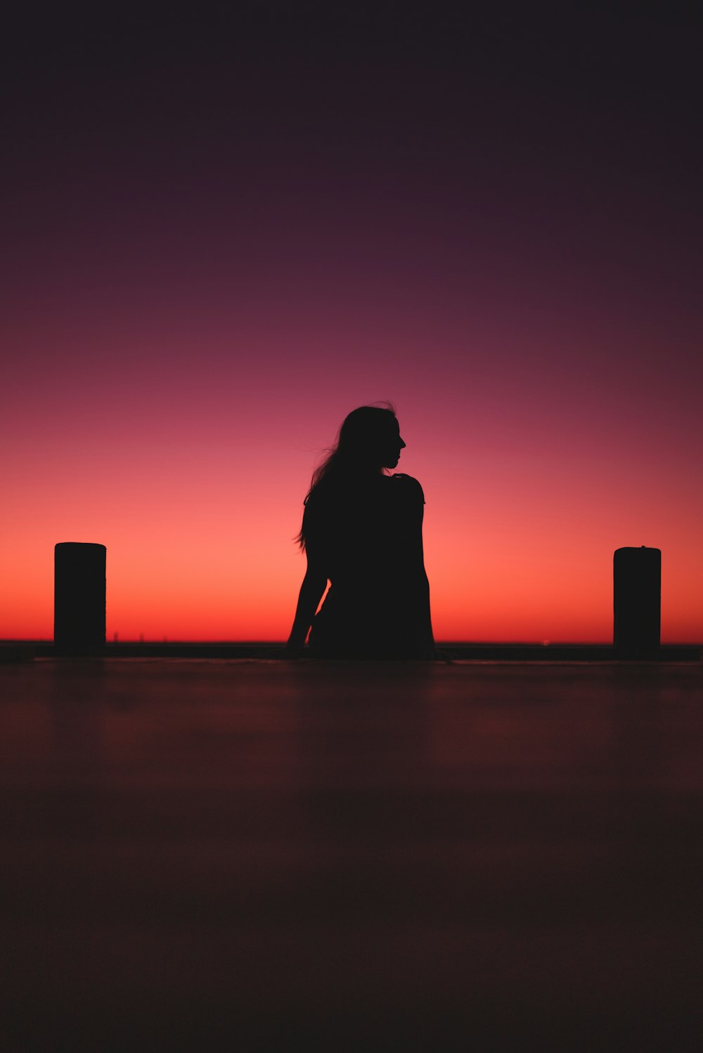 Silueta del hombre y de la mujer de pie en la playa durante la puesta del sol